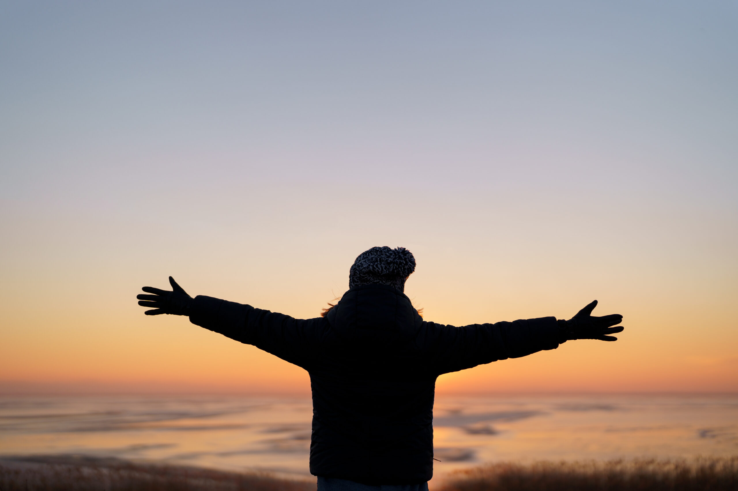 motivational image of a woman raising hands in the sunset